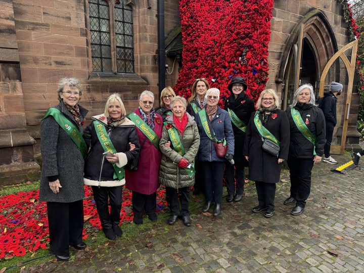 Members of Bedworth Belles WI standing beside the Poppy Installation at All Saints Church, Bedworth.